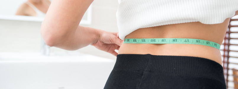 thin woman measuring her taille