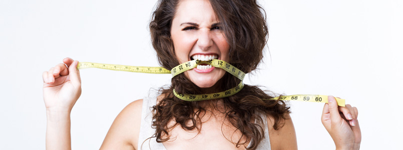 Frustrated woman biting on measuring tape