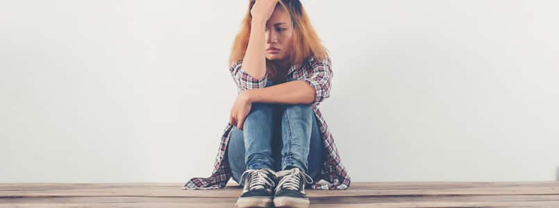 teenage girl sitting on the ground, looking depressed