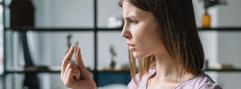 woman looking confusedly at pill