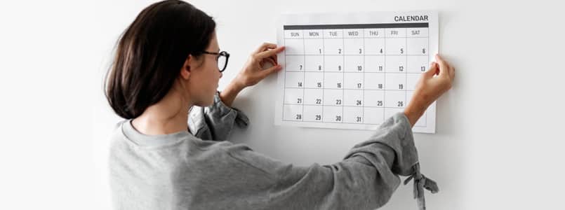 woman hanging calendar on wall