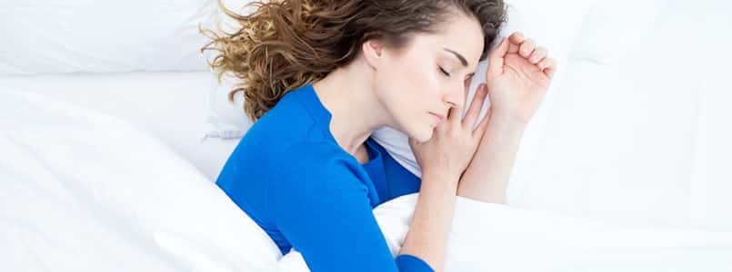 Woman sleeping restfully in her bed after taking melatonin