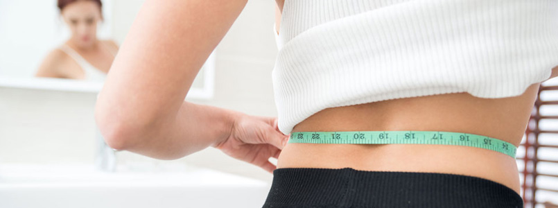 thin woman measuring waist