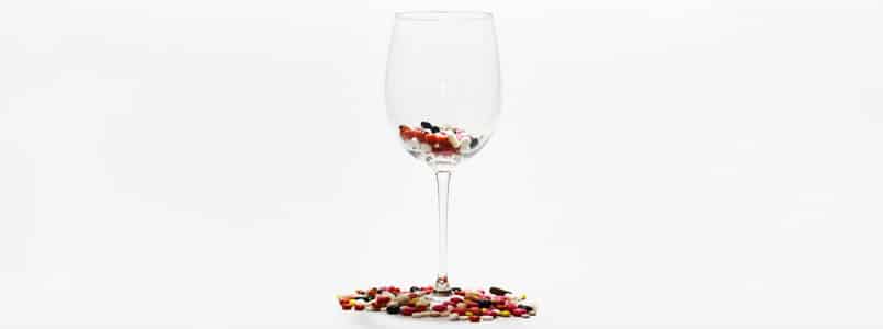 wine glass filled with prescription pills