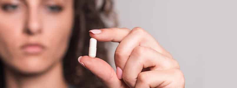 Woman examining white pill
