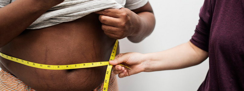 obese man having his waist measured