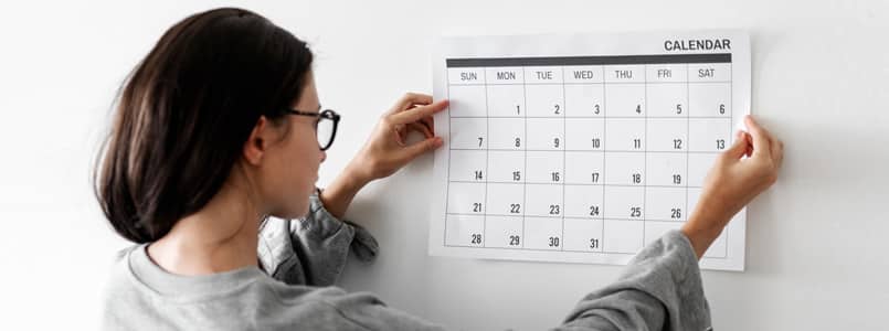 woman hanging calendar on wall