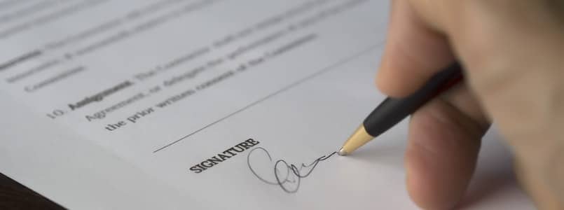hand holding pen and signing document